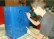Ein Junge malt die Umrisse der Figur, die auf den Abfalleimer gemalt werden soll mit einem schwarzen Stift nach.