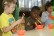 Drei Kinder probieren, mit Stäbchen Reis aus einer kleinen Schüssel zu essen.