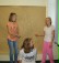 3 Mädchen stehen vor einer Wand auf der ein großes Stück Packpapier hängt.