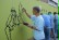 1 Lehrer und 4 Jungen zeichnen die Schablonenumrisse auf der grünen Wand mit schwarzer Farbe nach.