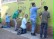 1 Lehrer und 4 Jungen zeichnen die Schablonenumrisse auf der grünen Wand mit schwarzer Farbe nach.