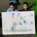 Zwei Jungen halten ein Bild mit aufgedruckten Händen vor sich.