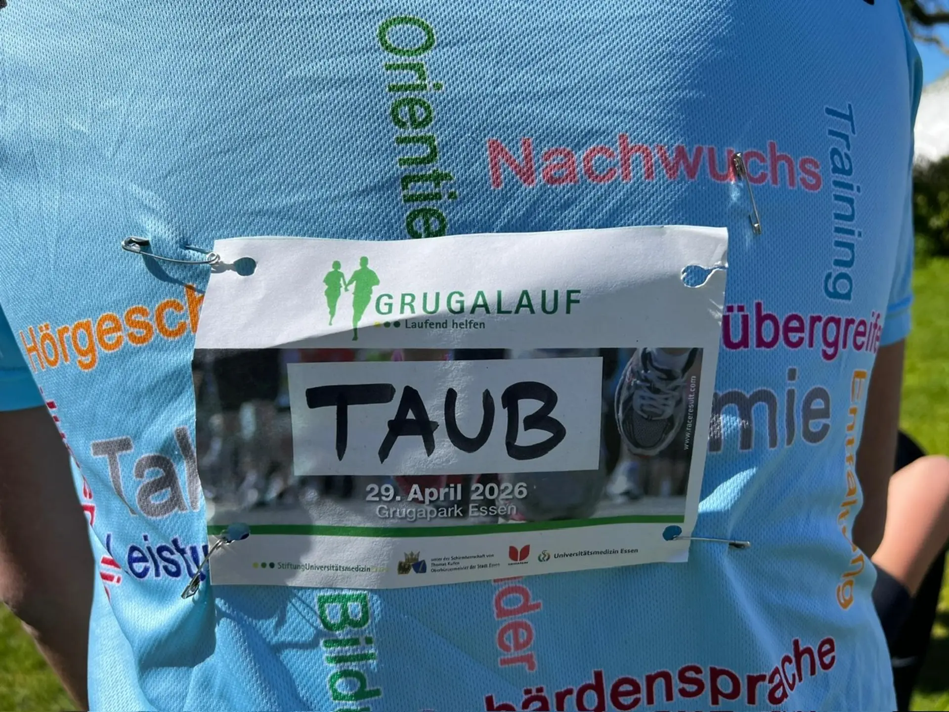 Ein Teilnehmer trägt ein Schild auf dem Rücken mit dem Hinweis "Taub".