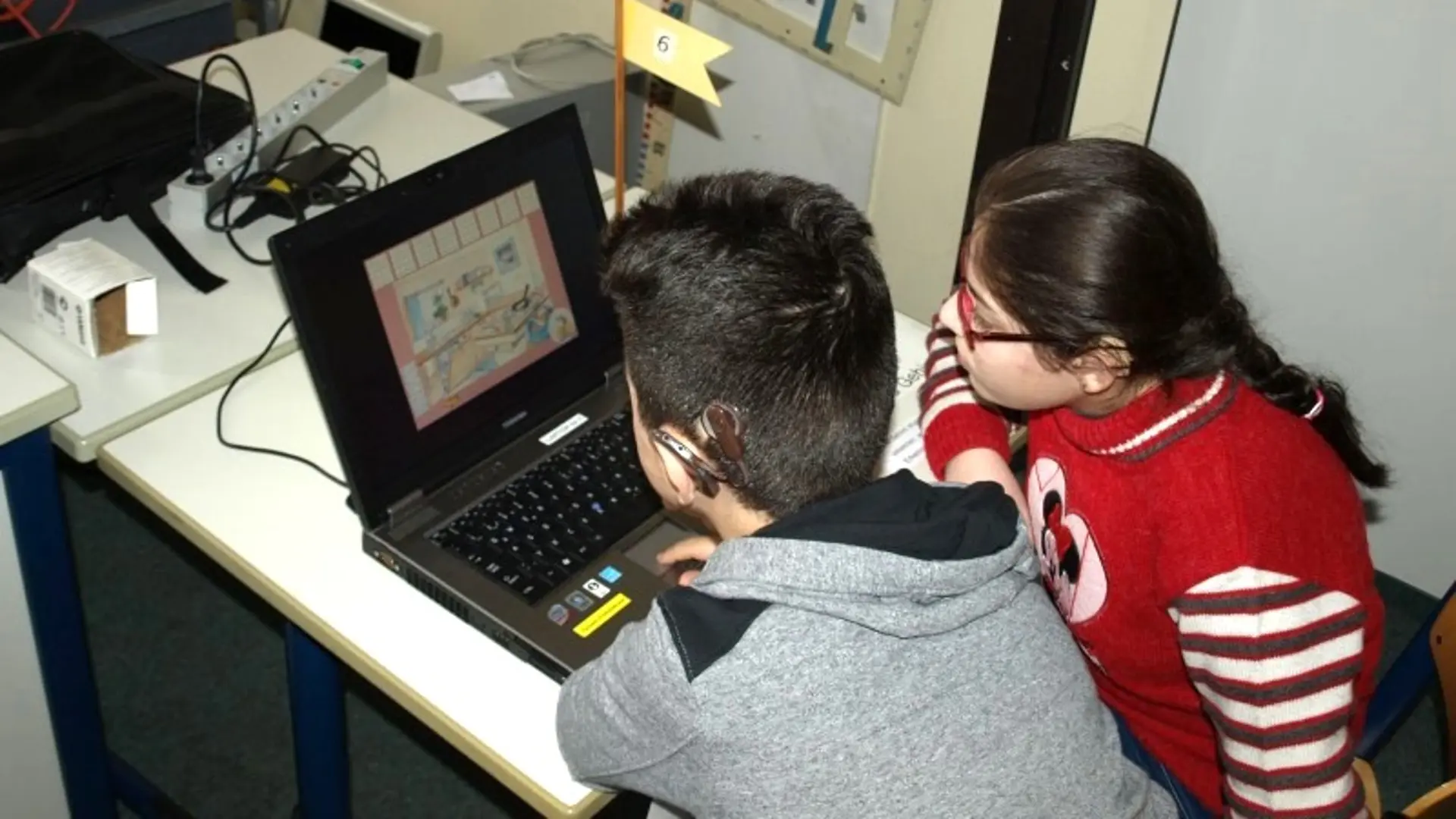 Buntes Gemälde des Maskottchens der Schule: ein fröhliches Flusspferd, dass die Arme in die Luft reckt. Es scheint zu tanzen. Es trägt ein Kleider das der Nationalflagge von Griechenland entspricht.