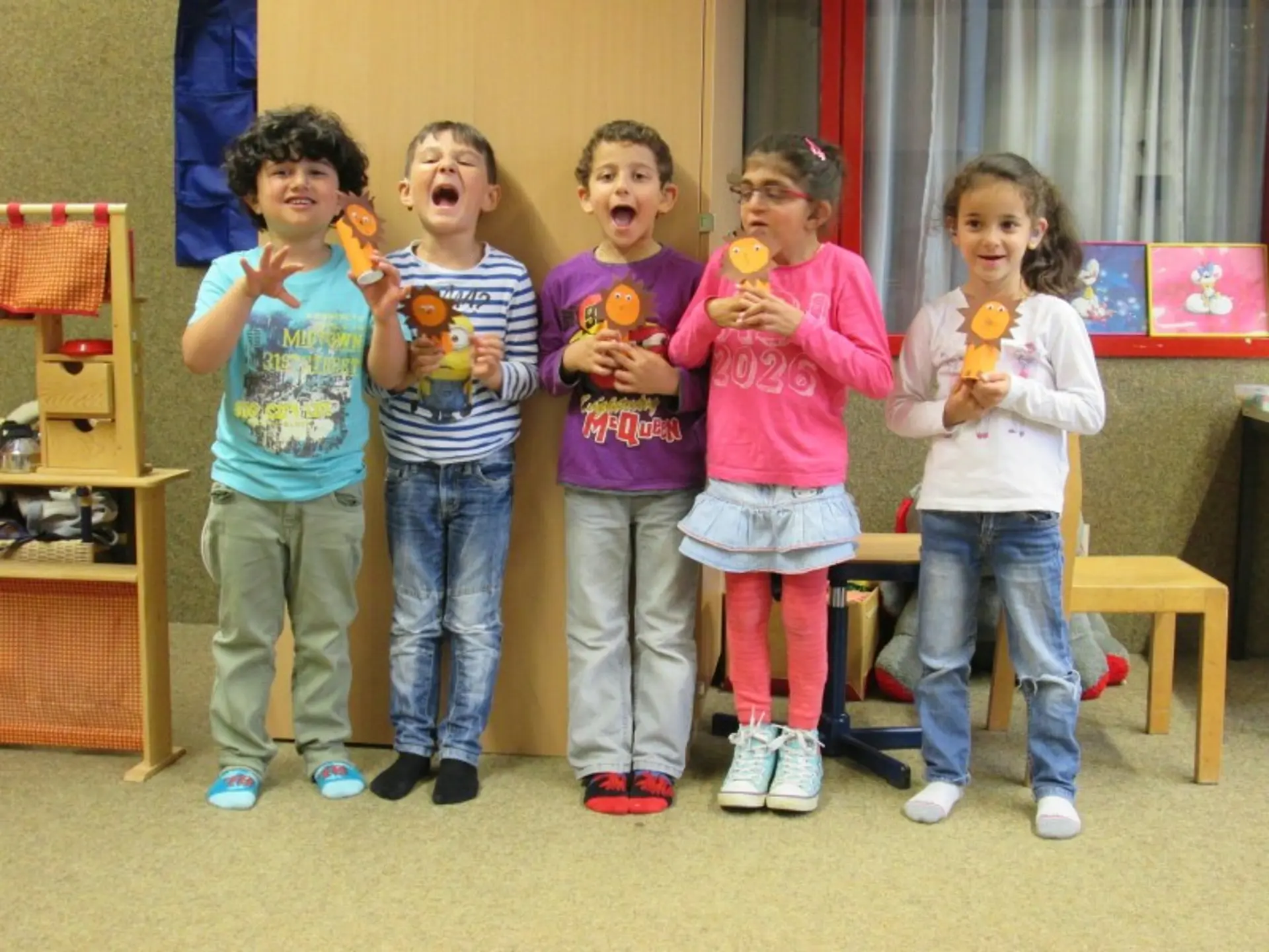 Fünf Kinder haben Löwen aus Klopapierrollen gebastelt und zeigen ihn fröhlich in die Kamera.