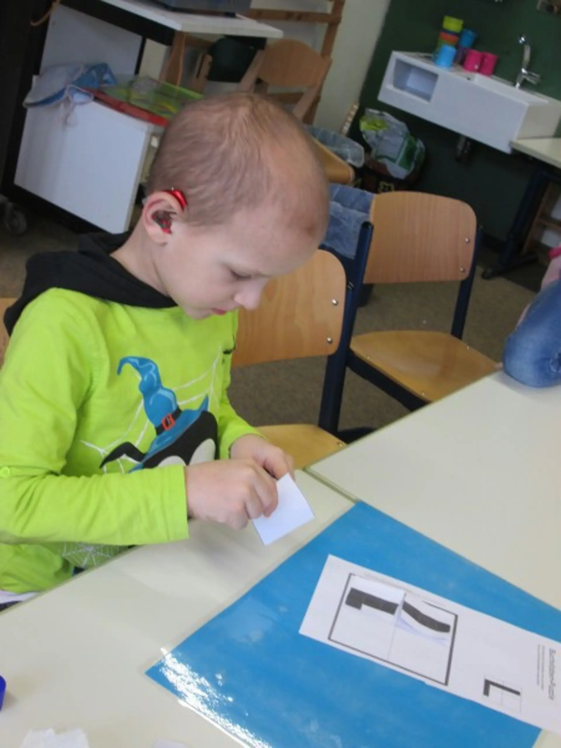 Ein Kind klebt den Buchstaben L aus einzelnen Puzzleteilen auf ein Blatt.